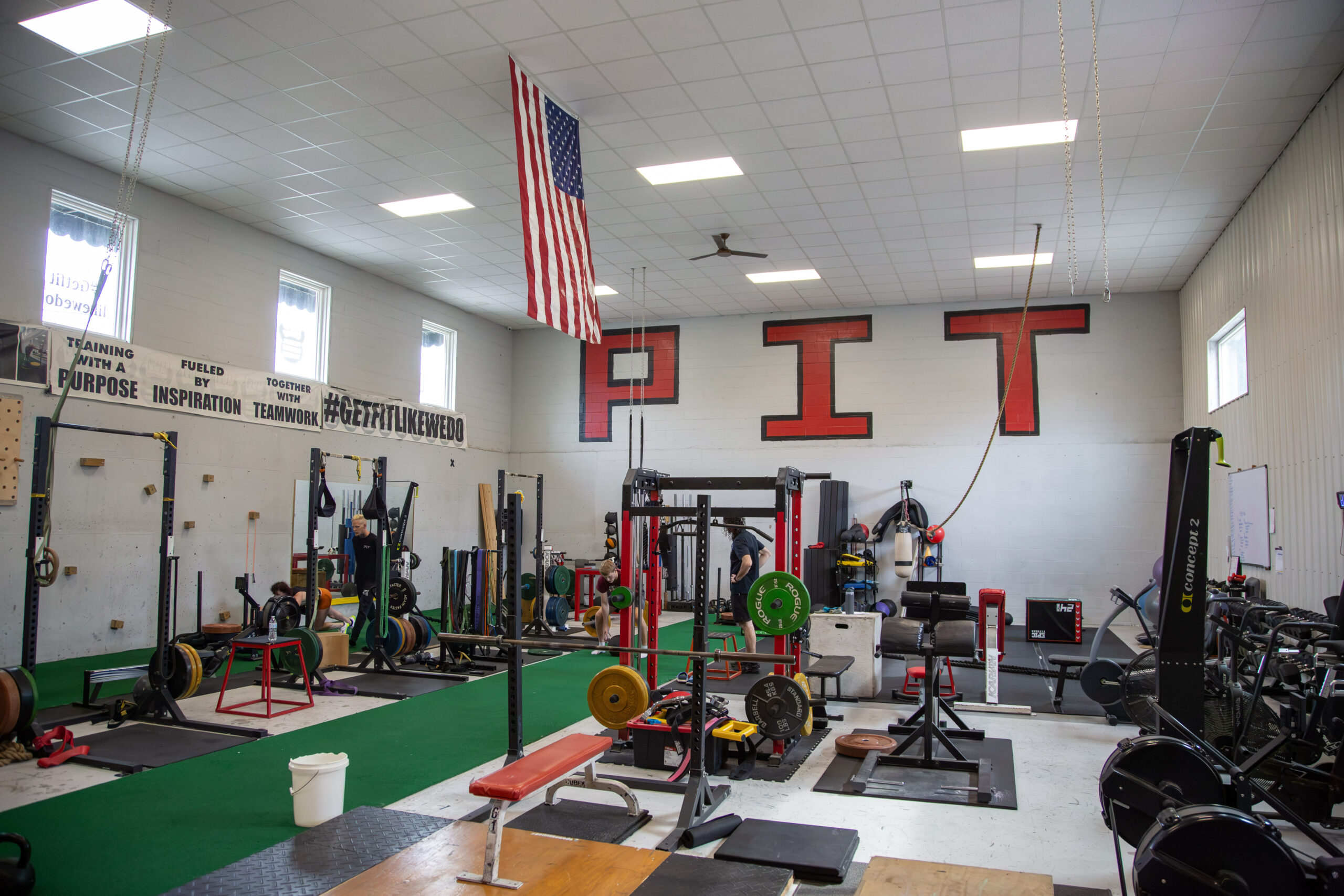 Wide interior view of the Physical Industry Training gym with turf, racks and training equipment
